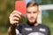 Referee hands with red card on football field