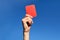 Referee hands with red card on football field