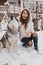 Refined female model in warm clothes fooling around with husky dog during winter holidays. Outdoor portrait of stunning