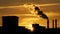 Refinery plant silhouette with chimney smoke against sunset