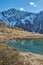 Reflecting mountain lake in front of snowy mountain peaks. Mountain landscape with reflecting lake and snowy mountains. Glacial