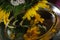 Reflection of bouquet of sunflower flowers and various meadow flowers in large metallic plate on dark background