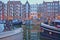 Reflection of colorful heritage buildings along Brouwersgracht Canal in Amsterdam, with houseboats in the foreground