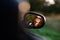 Reflection of a gorgeous young dark-haired girl in sunglasses in a side mirror of a car.