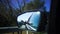 Reflection of hand unrecognized passenger in the side mirror of a moving car along sunny daily street during traveling