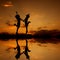 Reflection of Happy of two women jumping and sunset silhouette