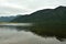 Reflection of a high mountain in the waters of a calm lake on a cloudy summer day