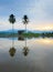 Reflection of hills, a hut and coconut trees