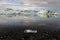 Reflection of ice cubes with black gravel and small ice cube foreground at Jokulsarlon Glacier Lagoon