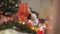 Reflection of joyful cute Middle Eastern boy shaking New Year present sitting at table with family in living room