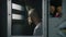 Reflection of male prisoner in mirror looking out the window in prison cell