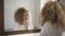 Reflection in mirror of Caucasian redhead woman brushing teeth in bathroom. Portrait of concentrated adult lady taking