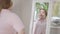 Reflection in mirror of confident chubby Caucasian woman. Portrait of self-assured young overweight lady at home in the