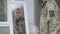 Reflection in mirror of confident handsome middle aged man adjusting military uniform indoors. Portrait of serious