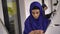 Reflection in mirror of young muslim woman in hijab trying on necklace and bracelet in jewelry shop