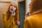 Reflection in a mirror of a young Spanish redhead woman applying pink lipstick