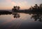 Reflection of pink clouds and traces of aircraft in the water of a pond