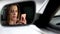 Reflection in rearview mirror, beautiful woman scrolling news on mobile phone
