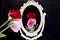 Reflection of rose in vintage mirror on black background