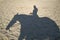 Reflection on the sand a man riding a horse silhouette rider