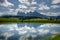 Reflection of Sassolungo and Langkofel mountain group and cloudy blue sky in lake, Picturesque. Alpe di Siusi or Seiser Alm with