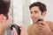 Reflection of shirtless man shaving with electric razor