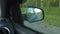 Reflection side rear view car mirror in the morning on the road at sunset or sunrise. Travelling reflection of trees and