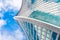 Reflection of sky and clouds in glass spiral, wave with bend facade windows of financial skyscrapers.