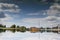 Reflection on smooth surface of river of buildings, trees, blue sky and clouds. Symmetry. Inverted picture.