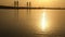 Reflection of sunset in rippling river. Silhouette of bridge and city skyline at dusk. Yellow misty sky