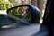 Reflection of teenage girl in wing mirror standing beside a car