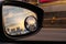 Reflection of traffic flow on asphalt road in side mirror of blue SUV. Car wing mirror with convex mirror for safety driving. View