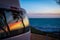 Reflection of tree silhouettes on camper van window in front of Indian Ocean in Australia