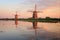 Reflection of two traditional windmills in the water at sunset