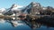 Reflection in the water. Snowy mountains, fishing village, red rorbu houses, and their peaceful reflections on the water