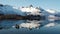 Reflection in the water. Snowy mountains, fishing village, red rorbu houses, and their peaceful reflections on the water