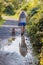 Reflection in water surface of a puddle, senior adult woman walking with her dog