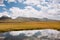 Reflection of white clouds in artificial reservoir of the Central Asian mountains. Sunny scene