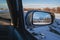 reflection of winter landscape with Tien Shan mountains and trees in field in snow in rearview mirror of car. Concept of