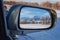 reflection of winter landscape with Tien Shan mountains and trees in field in snow in rearview mirror of car. Concept of