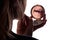 Reflection of a woman doing makeup in front of a pocket mirror in hands
