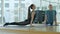 Reflection of young woman and mid-adult man practicing yoga indoors. Wide shot of confident strong Caucasian yogi doing