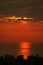 Reflections of the setting sunlight over the sea with skyscraper silhouette in foreground