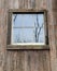 Reflections of the sky and trees in the old weathered wood farm building glass window