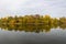 Reflections of trees in autumn colors under the cloudy sky, in Herestrau Park in northern Bucharest