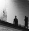 Reflections of two people on the rippled surface of a canal in t