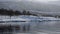 Reflective sea surface with slow falling snow and calm waves and sky clouds