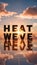 Reflective surface displaying bold HEAT WAVE letters amidst vibrant sunset or sunrise scene