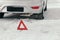 Reflective warning triangle before vehicle, an emergency situation on the road in winter, calls for help. car broke down