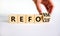 Refocus and reform symbol. Businessman turns a wooden cube and changes the word refocus to reform. Beautiful white table, white